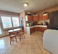 5.izb RD Čereňany pozemok 1028m - Kuchyňa v rodinnom dome s nábytkom z dreveným dekorom, jedálenským stolom a spotrebičmi.