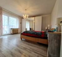 5.izb RD Čereňany pozemok 1028m - Svetlá spálňa s lusterom, veľkým oknom a podlahou s dreveným dekorom v rodinnom dome.