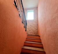 5.izb RD Čereňany pozemok 1028m - Schodisko v rodinnom dome s tehlovou stenou a oknom na konci.