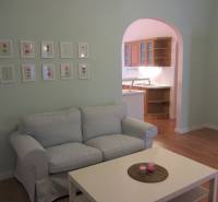 4-izb.byt v centre mesta, Obchodná ul., BA I - Staré Mesto, 2 x balkón - Obývačka 4-izbového bytu s pohovkou, stolíkom a kuchynským kútom, podlaha s dreveným dekorom.