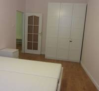 4-izb.byt v centre mesta, Obchodná ul., BA I - Staré Mesto, 2 x balkón - Spálňa s bielou skriňou, posteľou a podlahou s dreveným dekorom v 4-izbovom byte.