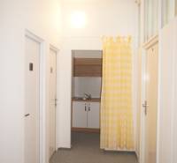 Kancelárie, Drieňová ul., Ružinov 25 m2 - Úzka chodba s dverami a žlto-bielym závesom, vedúca ku kuchynskému kútiku v kancelárii.