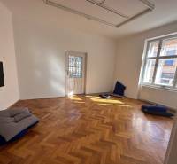 3,5 izb. byt v priamo centre Bratislavy na pešej zóne - Miestnosť v 4-izbovom byte s podlahou s dreveným dekorom a vankúšmi na zemi.