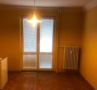 1-izb. byt na ul. Račianska, Nové Mesto s lodžiou - Žlté steny, podlaha s dreveným dekorom, radiátor a svetlo v 1-izbovom byte.