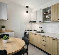 R E Z E R V O V A N Ý 3 izbový byt s balkónom , Košická, Komárno - Kuchyňa v 3-izbovom byte s dreveným dekorom, bielymi kachličkami a okrúhlym stolom.