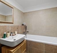 I Na predaj priestranný 2-izbový byt v Rovinke (City Park) - Kúpeľňa s umývadlom, zrkadlom a vaňou v 2-izbovom byte, svetlé obklady.