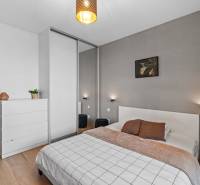 I Na predaj priestranný 2-izbový byt v Rovinke (City Park) - Spálňa v 2-izbovom byte s podlahou s dreveným dekorom a moderným nábytkom.