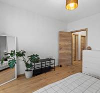 I Na predaj priestranný 2-izbový byt v Rovinke (City Park) - Izba v 2-izbovom byte s bielym nábytkom, zrkadlom a podlahou s dreveným dekorom.