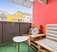 Na predaj moderný 2-izb. byt s loggiou vo Vrábľoch - Balkón s paletovým nábytkom a stolíkom, farbené budovy vo Vrábľoch, 2-izbový byt.