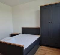 Zariadený 2-izb. byt v novostavbe v Ružinove - Ovocné sady - Spálňa v 2-izbovom byte obsahuje posteľ, nočný stolík, šatník a podlahu s dreveným dekorom.