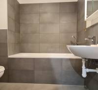 Zariadený 2-izb. byt v novostavbe v Ružinove - Ovocné sady - Kúpeľňa s vaňou, umývadlom a práčkou v 2-izbovom byte. Šedé obkladačky dominujú priestoru.