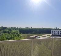 Zariadený 2-izb. byt v novostavbe v Ružinove - Ovocné sady - Výhľad z balkóna v Bratislave - Ružinov na Ivanskej ceste s budovami a zeleňou.