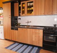 Veľký 1-izb. byt v tehlovom dome, Miletičova ul., Ružinov  - Kuchyňa s drevenou linkou, podlahou s dreveným dekorom, plynovým sporákom a chladničkou.