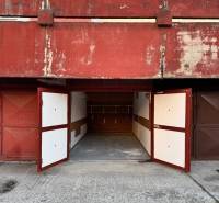 Garáž Bebravská ul., Vrakuňa s pozemkom - Garáže na Bebravskej ulici v Bratislave - Vrakuni s otvorenými kovovými bránami.