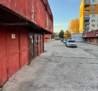 Garáž Bebravská ul., Vrakuňa s pozemkom - Garáže na Bebravskej ulici v Bratislave - Vrakuni, vedľa obytných domov a áut.