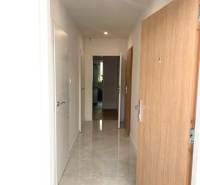 4-izb. byt, Cabanova ul., Dúbravka so samostatným vstupom - Úzka chodba so svetlými stenami a dlažbou, vchod na ulici Cabanova.