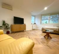 4-izb. byt, Cabanova ul., Dúbravka so samostatným vstupom - Obývacia izba so žltou sedačkou, TV a dreveným stolom v 4-izbovom byte na ulici Cabanova.