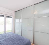 ZATON - Apartmán so záhradou - na predaj  - Spálňa v rekreačnom apartmáne s veľkou vstavanou skriňou a posteľou s modrou prikrývkou.