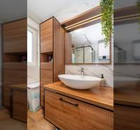 ZATON - Apartmán so záhradou - na predaj  - Kúpeľňa v rekreačnom apartmáne s umývadlom, dreveným nábytkom a podlahou s dreveným dekorom.