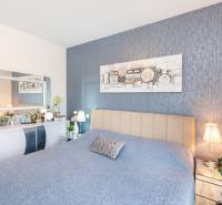 ZATON - Apartmán so záhradou - na predaj  - Spálňa v Rekreačnom apartmáne s modrým prehozom, dekoráciami a zrkadlom nad stolíkom.