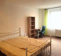 Pekný 2 izbový byt na prenájom - Malacky - Spálňa s posteľou, stolom, policou a podlahou s dreveným dekorom v 2-izbovom byte.