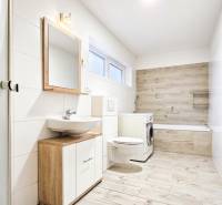 Na predaj kompletne zrekonštruovaný RD Bernolákovo -Trnavská - Kúpeľňa v rodinnom dome s podlahou s dreveným dekorom a práčkou.