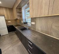 Novostavba rodinný dom Ludanice / REZERVOVANE - Kuchyňa v Rodinnom dome s dreveným dekorom a bielou chladničkou.