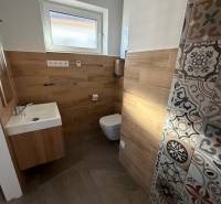 Novostavba rodinný dom Ludanice / REZERVOVANE - Kúpeľňa v rodinnom dome s umývadlom, WC a podlahou s dreveným dekorom.