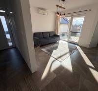 Novostavba rodinný dom Ludanice / REZERVOVANE - Obývacia izba v rodinnom dome s klimatizáciou a veľkým oknom, podlaha s dreveným dekorom.