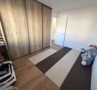 Novostavba rodinný dom Ludanice / REZERVOVANE - Detská izba v rodinnom dome s podlahou s dreveným dekorom a veľkou vstavanou skriňou.