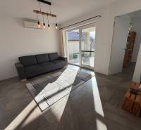 Novostavba rodinný dom Ludanice / REZERVOVANE - Obývačka v rodinnom dome s pohovkou, krémovými závesmi a presklenými dverami na terasu.