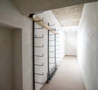 Prenájom haly / obchodno-skladových priestorov – Šenkvice, Nádražná ul - Úzky interiérový priestor v sklade s kovovými vešiakmi na stene.