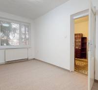 Byt, ktorý dáva zmysel pre rodinu – o 100 000 € lacnejší než dom. - Izba v 4-izbovom byte, biele steny, kobercová podlaha, veľké okno a dvere.