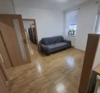 Na prenájom klimatizovaný 2 izbový byt v Moste pri Bratislave - Obývacia izba v 2-izbovom byte s podlahou s dreveným dekorom a pohovkou.