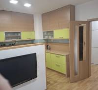 Na prenájom klimatizovaný 2 izbový byt v Moste pri Bratislave - Kuchyňa v 2-izbovom byte s podlahou s dreveným dekorom a farebnými skrinkami.