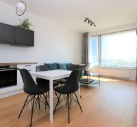 NUERA︱SKY PARK Moderný 2-izbový byt na 6. poschodí, veža 3 - Kuchyňa a jedálenský stôl s čiernymi stoličkami v 2-izbovom byte s podlahou s dreveným dekorom.