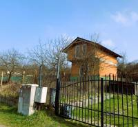 CHATA UZAVRETÁ HRUBÁ STAVBA, KOŠICKÁ NOVÁ VES - GEDER - Na obrázku je chata obklopená stromami a plotom na trávnatom pozemku.