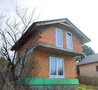 CHATA UZAVRETÁ HRUBÁ STAVBA, KOŠICKÁ NOVÁ VES - GEDER - Dvojpodlažná chata v rozostavanom stave, obklopená stromami a trávou na vidieckom pozemku.