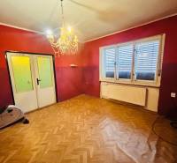 Predaj staršieho RD vo Dvoroch nad Žitavou - Izba v rodinnom dome s lustrom a podlahou s dreveným dekorom.