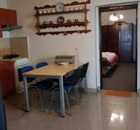 Na Predaj Rodinný dom pozemok 1587 m² v Horných Salibách  - Jedálenský stôl so stoličkami v rodinnom dome, kuchynská časť a otvorené dvere do spálne.