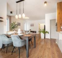 Rezervované 3-izbový byt so záhradou, Šamorín - Jedálenská a kuchynská časť 3-izbového bytu s podlahou s dreveným dekorom a závesným osvetlením.