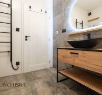 Rezervované 3-izbový byt so záhradou, Šamorín - Kúpeľňa s podlahou s dreveným dekorom, umývadlom a zrkadlom v 3-izbovom byte.