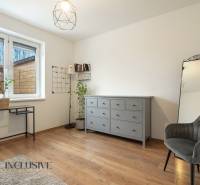 Rezervované 3-izbový byt so záhradou, Šamorín - Interiér 3-izbového bytu s podlahou s dreveným dekorom, sivou komodou a čalúneným kreslom.