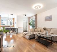 Rezervované 3-izbový byt so záhradou, Šamorín - Obývačka v 3-izbovom byte s pohovkou, jedálenským stolom a podlahou s dreveným dekorom.