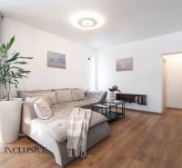 Rezervované 3-izbový byt so záhradou, Šamorín - Obývačka v 3-izbovom byte s podlahou s dreveným dekorom a pohodlnou sedačkou.