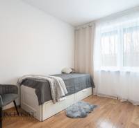 Rezervované 3-izbový byt so záhradou, Šamorín - Svetlá izba v 3-izbovom byte s posteľou, kreslom a podlahou s dreveným dekorom.