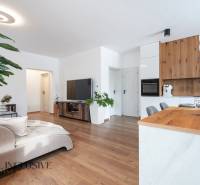 Rezervované 3-izbový byt so záhradou, Šamorín - Obývacia izba so sedačkou, dreveným dekorom a rastlinami v 3-izbovom byte.