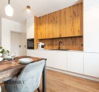 Rezervované 3-izbový byt so záhradou, Šamorín - Kuchyňa s bielymi skriňami a podlahou s dreveným dekorom v 3-izbovom byte.