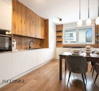 Rezervované 3-izbový byt so záhradou, Šamorín - Kuchyňa v 3-izbovom byte s podlahou s dreveným dekorom, jedálenským stolom a veľkým oknom.