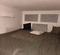 – PRENAJOM – 3 IZBOVÝ BYT – STARE MESTO  - Spálňa v 3-izbovom byte s nízkym stropom, pukovými panelmi na stene a podlahou s dreveným dekorom.